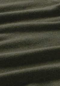 Tmavě zelená látka s měkkým, texturovaným povrchem, která vykazuje vlnitý vzor. Materiál vypadá teple a útulně, vhodný na oblečení nebo deky.