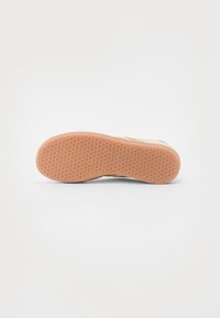 Gummischal med ett texturerat bikake-mönster; beige färg med en slät kant och en lätt kurva vid tån.