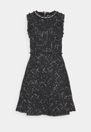 Czarna sukienka bez rękawów z tkaniny tweedowej o fakturowanym wzorze. Posiada okrągły dekolt ozdobiony koralikami; rozkloszowany dół z postrzępionym brzegiem.