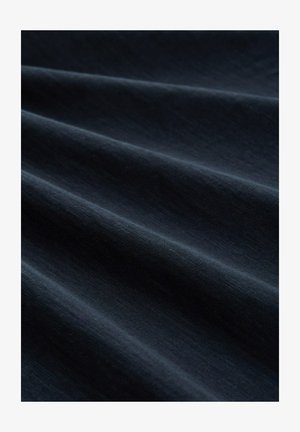 Tumedat merevaigust sinist kangast, millel on pehmed voldid ning nähtav peen kootud tekstuur ühtlase valgustuse all.