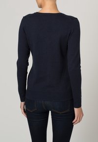 Marineblaues Strickpullover mit Rundhalsausschnitt. Verfügt über lange Ärmel und einen gerippten Saum, hergestellt aus einem weichen Stoff mit glatter Textur.