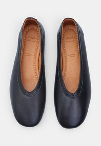 Bailarinas de cuero negro con punta redondeada, que presentan un exterior liso y una plantilla de cuero marrón. Sin hardware visible ni patrones.