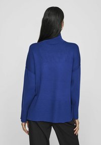 Maglione blu oversize con collo alto, orlo a costine e spalle scese. Texture liscia con vestibilità morbida.