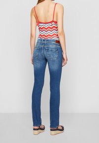 Smala jeans i mörkblå denim med medelhög midja, bakfickor och subtila blekningar. Bärs med en flerfärgad zigzag-top.