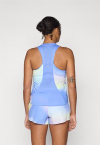 Top deportivo de color azul claro con espalda de malla, combinado con pantalones cortos suaves en un degradado pastel. Presenta un diseño de espalda de nadador y costuras planas.
