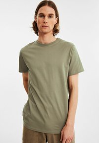 Olivengrøn kortærmet t-shirt i glat stof med rund halsudskæring, der har en afslappet pasform og minimale syninger.