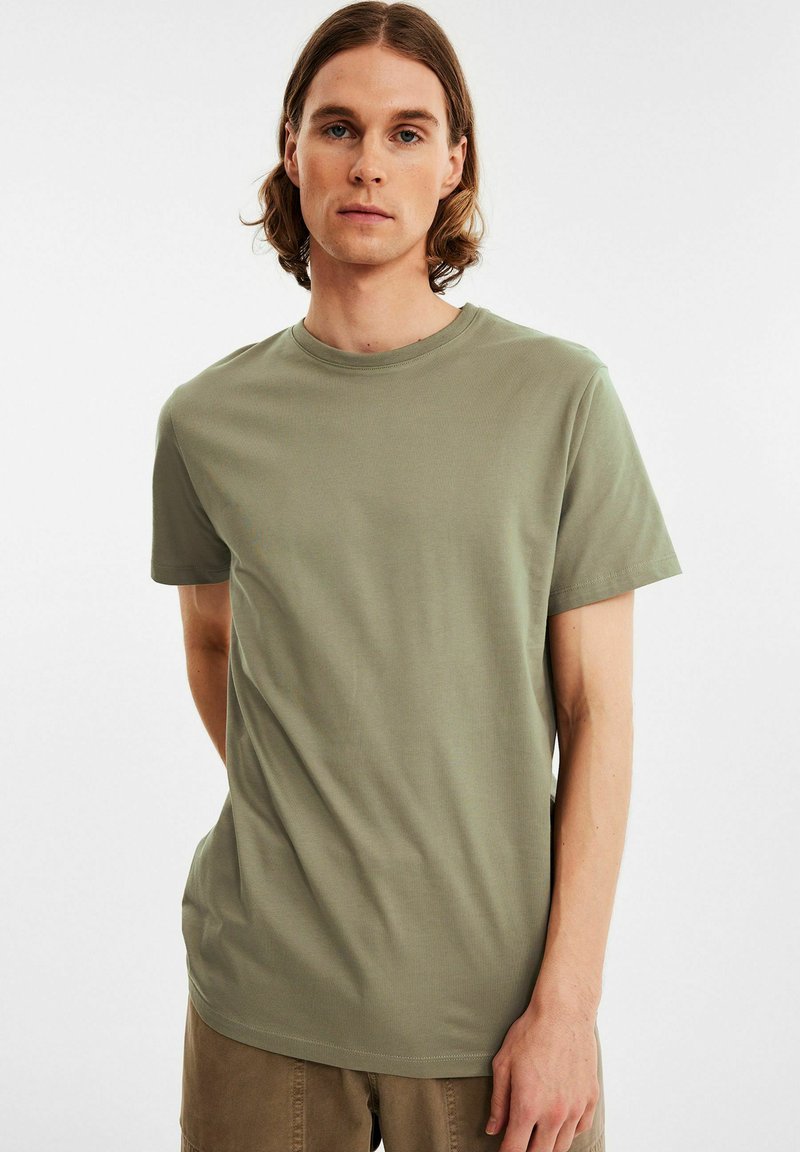 Olivengrøn kortærmet t-shirt i glat stof med rund halsudskæring, der har en afslappet pasform og minimale syninger.