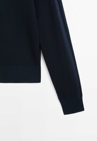 Marinblå stickad tröja med ribbade ärmar och nederkant, med en strukturerad tyg och en avslappnad passform. Ärmen sträcker sig förbi axelsömmen.