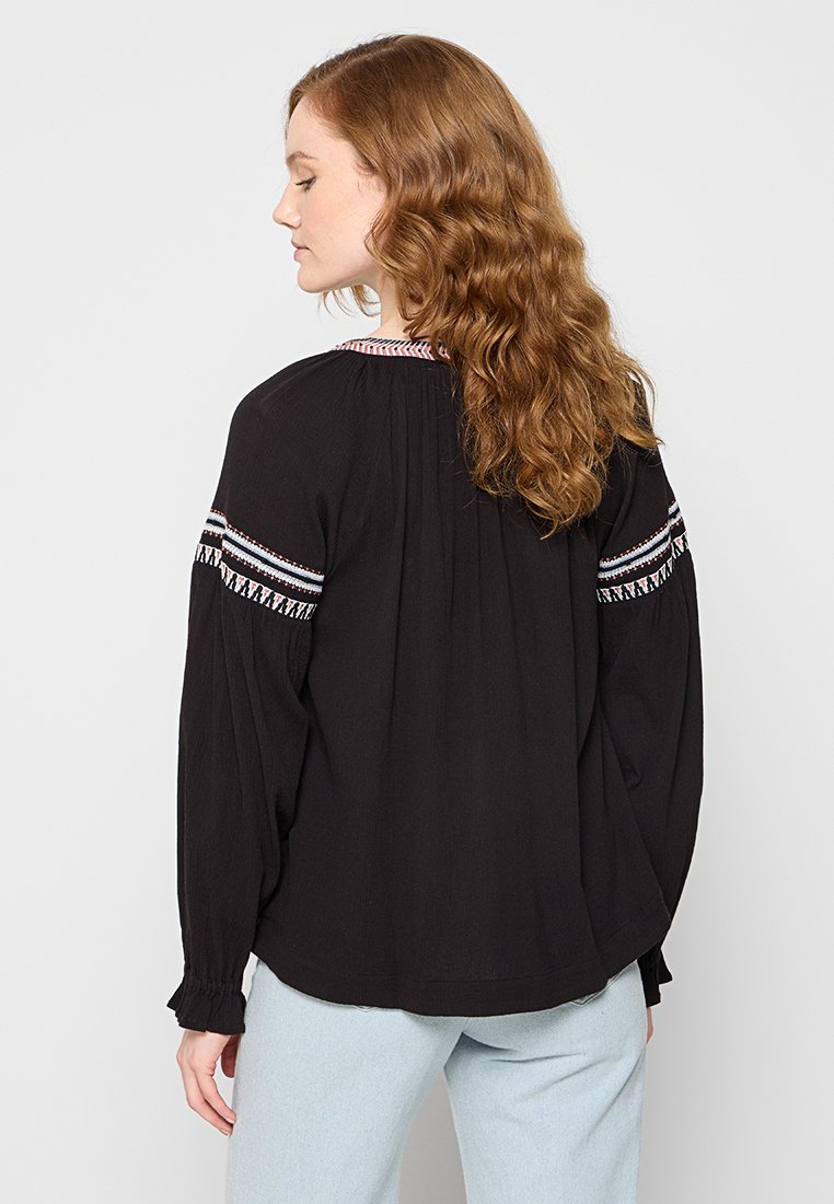 Schwarze Bluse mit langen Ärmeln, die mehrfarbige Stickereien aufweist, mit lockerer Passform und gerafften Details an den Ärmeln und am Ausschnitt.