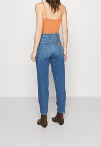 Džínové kalhoty s vysokým pasem v modré barvě, s volným střihem, které mají zadní kapsy se švy a hnědou koženou nášivku s logem.