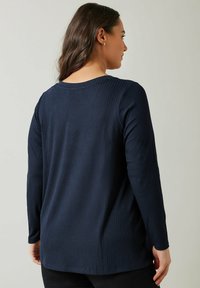 Top a maniche lunghe in blu navy a coste, con scollatura rotonda e orlo dritto, realizzato in tessuto morbido, caratterizzato da una superficie liscia e maniche aderenti.