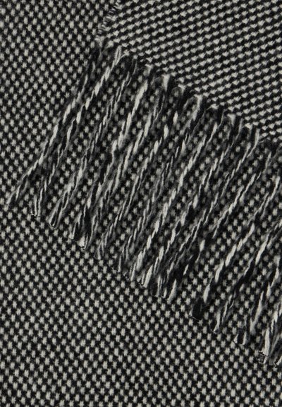 Tecido de padrão pied-de-poule em preto e branco com bordas franjas, mostrando textura e fibras macias entrelaçadas.