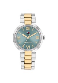 Reloj en tonos plateado y dorado con una esfera redonda, dial en color aqua, números romanos y embellishments de cristal alrededor del bisel. Presenta una pulsera con eslabones.
