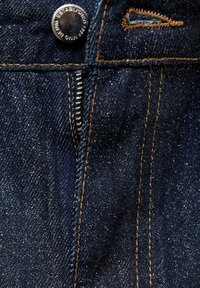 Tmavé džíny z denimu s viditelným šitím, kovovým knoflíkem a zipem. Tkanina má mírný lesk a texturovaný vzhled.