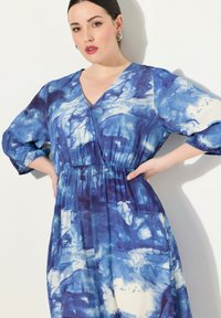 Modré tie-dye maxi šaty s V-výstřihem, tříčtvrtečními rukávy, elastickým pasem a splývavým siluetou. Hladká tkanina s jemnou texturou.