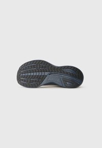 Shoe sole with a textured black rubber surface, featuring a wave pattern and grooves for grip, and a blue accent along the edge.
