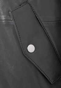 Schwarzes Ledergewebe mit einer glatten Textur, das mit einem kontrastierenden schiefergrauen Klappen und einem silbernen Druckknopf-Akzent versehen ist.