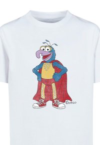 White t-shirt featuring a cartoon character with blue fur, oversized beak, red cape, yellow bodysuit, and red sneakers; hand-drawn style.