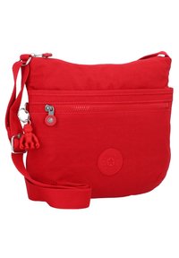Rød crossbody taske, lavet af stof, har et lynlåset hovedrum, frontlomme, justerbar rem og en lille abe nøglering.