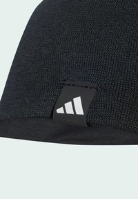 Black knit beanie with lightweight, textured fabric. Features a black label with white three-stripe logo on the side. Smooth hem.