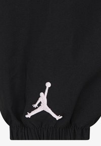 Pantaloni jogger neri con polsini elastici e logo Jordan ricamato in pose di salto. Tessuto morbido e liscio.