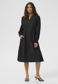 Zwarte denim jurk met een knoopsluiting bij de henley-halslijn, lange mouwen en zakken, met een licht uitlopende rok en een gestructureerde stof.