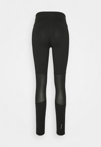 Svarta leggings med hög midja, med nätpaneler vid vadarna och små accentdetaljer vid fållen. Slitstarkt och elastiskt material.