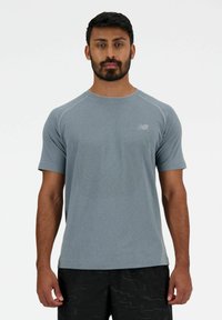 Maglietta atletica grigia a maniche corte, con un motivo testurizzato e un logo discreto. Cuciture a contrasto lungo le spalle.