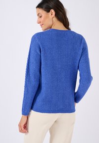 Blauwe gebreide trui met een verticale ribbelpatroon, ronde halslijn en lange mouwen. Zachte textuur met subtiele details op de stof.