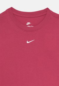 T-shirt Nike bordeaux avec un col rond, des manches courtes et un petit logo Nike blanc sur la poitrine. Matériau en coton doux avec une texture lisse.