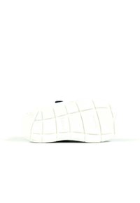 Semelle en caoutchouc blanche avec un motif en grille texturé, présentant des bords arrondis et une petite empreinte de logo sur la surface.