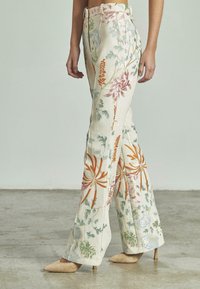 Pantaloni a campana floreali in tessuto leggero, con motivi di fiori ricamati multicolori e vita alta con passanti per cintura.
