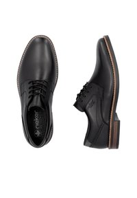 Zapatos de cuero negros con un acabado suave y acentos texturizados, que cuentan con un diseño de cordones, suela marrón en contraste y un logo en el costado.