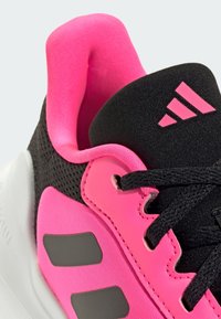 Baskets noires avec des accents rose vif. Présentent un col rembourré, un tissu texturé, des lacets noirs et un logo à trois rayures en rose. Semelle extérieure blanche.