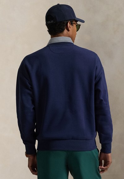 Μπλε φούτερ με ραβδωτό ντεκολτέ και μανσέτες, με αντίθετο ριγέ γιακά. Λείος βαμβακερός υφασμάτινος, σετ με πράσινο παντελόνι.