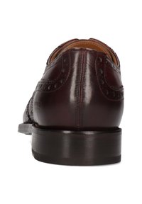 Scarpe brogue in pelle bordeaux scuro con perforazioni decorative, finitura liscia e suola piatta in pelle nera. Cuciture dettagliate visibili.
