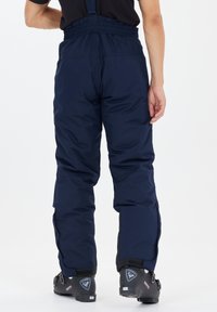 Marineblå snöbyxor med en stretchig midja, justerbara band och avsmalnande ben. Materialet verkar väderbeständigt med en slät textur.