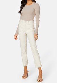 Beige ribbed lange mouwen top gecombineerd met witte hoge taille rechte broek en beige gevlochten hak sandals. Simpel, aansluitend ontwerp.