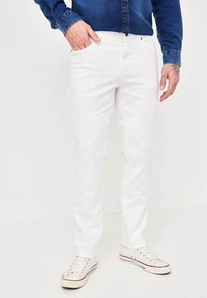White denim pants with a slim fit, featuring front pockets and a smooth texture, paired with white sneakers and a blue button-up shirt.