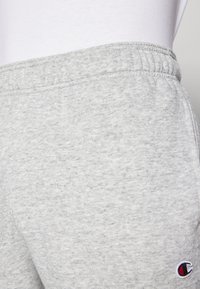 Grijze sweatpants gemaakt van zachte, gestructureerde stof; heeft een elastische tailleband en een kleine logopatch in rood, wit en blauw.