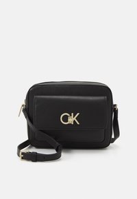 Borsa a tracolla in pelle nera con logo dorato, chiusura con zip e tracolla regolabile. Presenta una tasca anteriore e una finitura liscia e testurizzata.