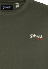 Camiseta verde oliva con cuello redondo, hecha de algodón suave. Presenta bordado en blanco y rojo de "Schott" y "N.Y.C". Etiqueta de talla L visible.