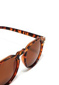 Želvovinové sluneční brýle s hnědými skly, kulatými obroučkami a charakteristickým mostíkem ve tvaru klíče. Pruhovaný vzor na nožičkách.