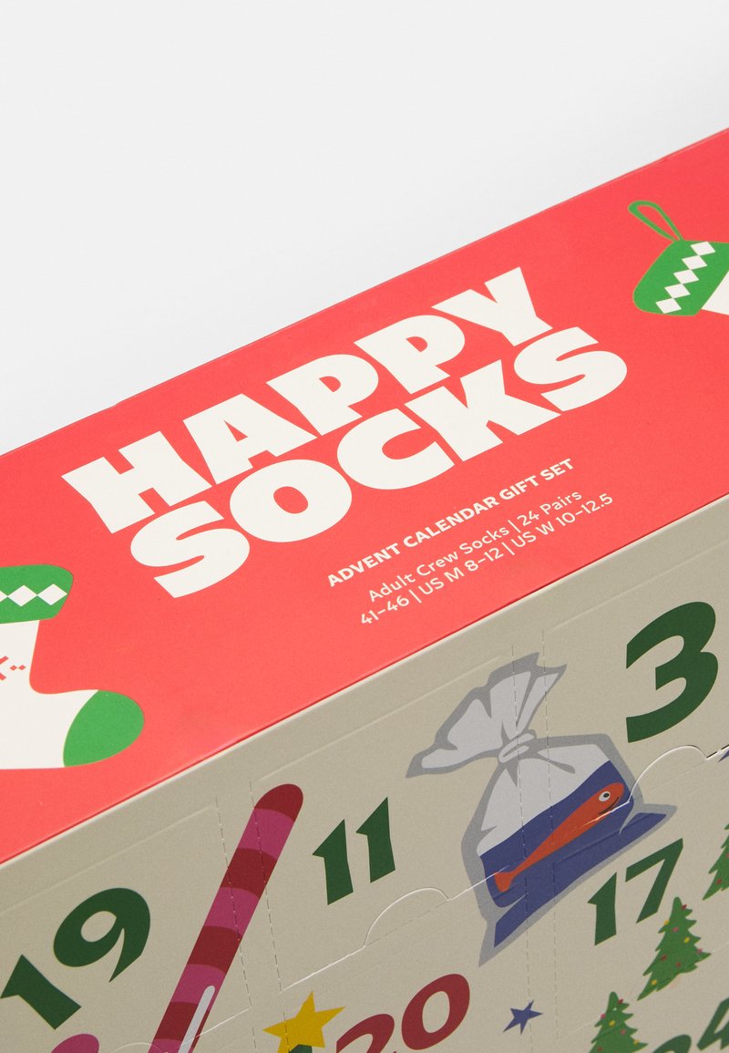 Zestaw prezentowy z kalendarza adwentowego z czerwonym topem z białym napisem "HAPPY SOCKS" oraz ilustrowanymi akcentami, takimi jak cukierki w kształcie lasek i skarpetki po bokach.