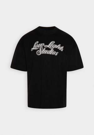 Sort oversized T-shirt med hvid kursiv tekst "Low Lights Studios" på fronten, korte ærmer og rund hals.