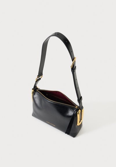 Sac à épaule en cuir noir avec boucle et fermeture éclair dorées, partiellement ouvert pour montrer la doublure intérieure rouge foncé, marquage Marc Jacobs à l'avant.