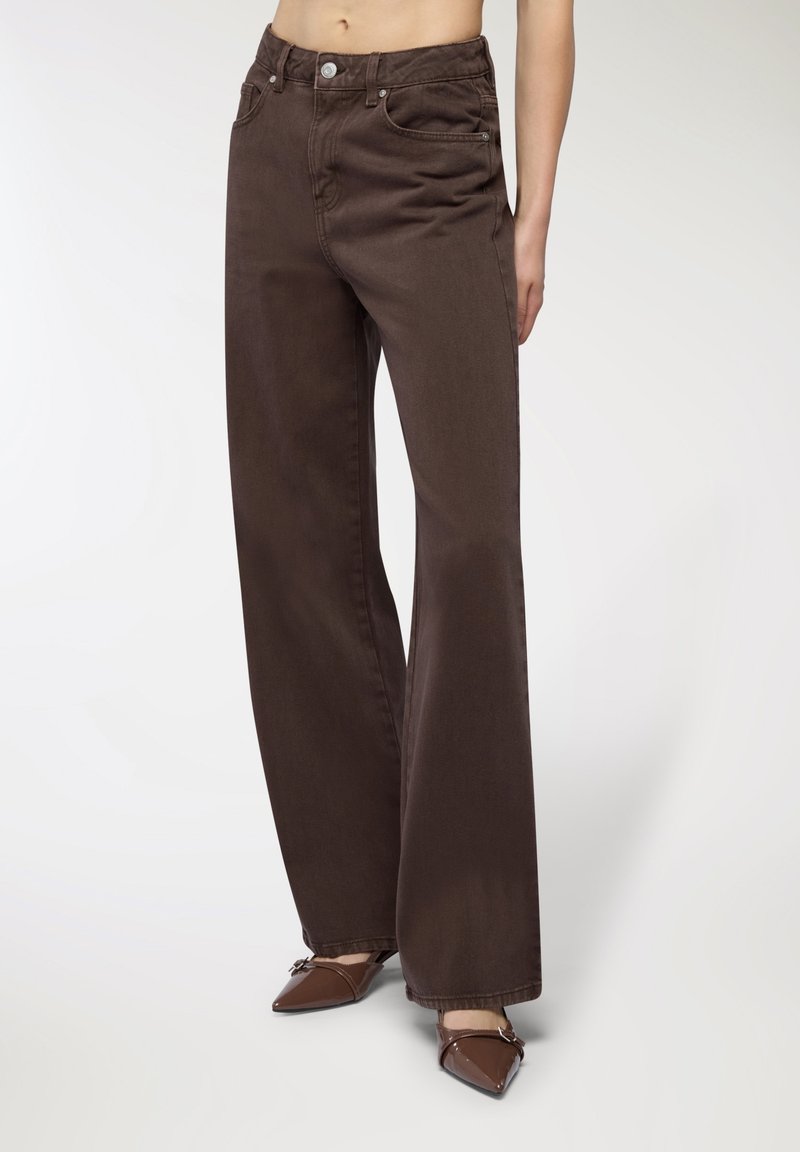 Brązowe dżinsy o szerokich nogawkach, wykonane z miękkiego denimu bawełnianego, z wysokim stanem, przednimi kieszeniami i subtelnymi detalami w przeszyciach.
