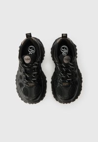 Încălțăminte sport neagră cu un superior sintetic texturat, panouri din plasă și o talpă groasă din cauciuc. Prezintă șireturi albe și accente cu logo.