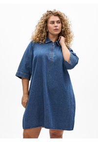 Tummansininen farkkupaitamekko, jossa on kaulus, puolivälissä oleva vetoketju ja kyynärpäänmittaiset hihat. Rentoutunut istuvuus ja sileä pinta.