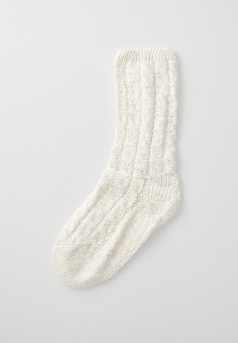 White knitted sock with a textured cable pattern and a ribbed cuff. Made from soft material, featuring a smooth toe and reinforced heel.